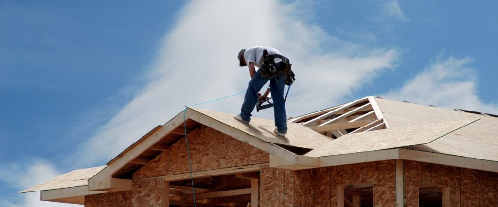 man standing on new home to prepare for new roof